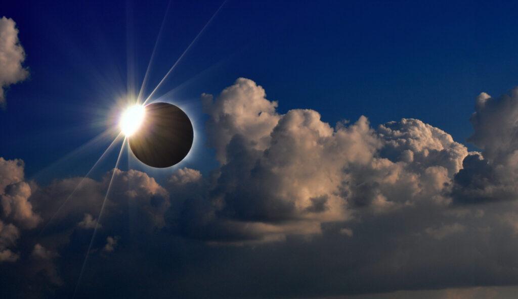 A partial solar eclipse in a blue sky with clouds